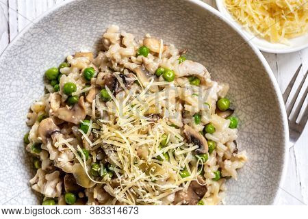 Mushroom risotto in stylish gray bowl, with peas and shaved parmesan.