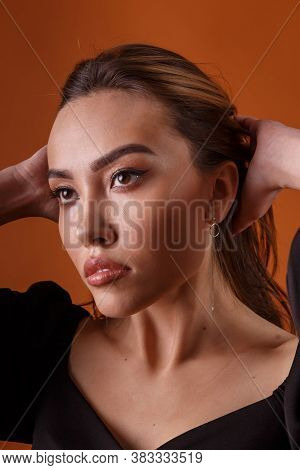 Charming Elegant Fashion Model Wearing Black Dress With Deep Neckline Posing On Orange Background. A