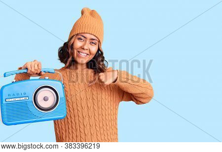 Young beautiful mixed race woman holding vintage radio pointing finger to one self smiling happy and proud 