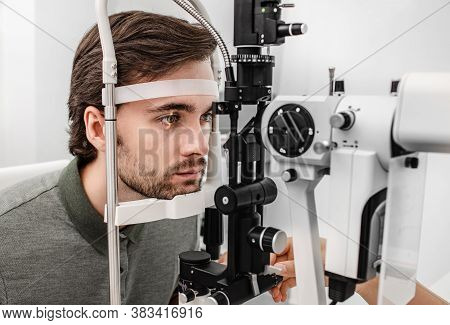 Adult Man Getting An Eye Exam At Ophthalmology Clinic. Checking Retina Of A Male Eye Close-up