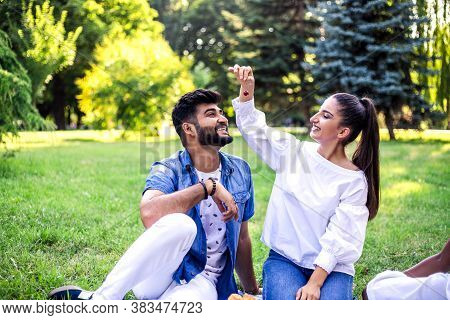 Young Multiracial Couple Feading Each Other And Have Fun On Picnic In The Park.