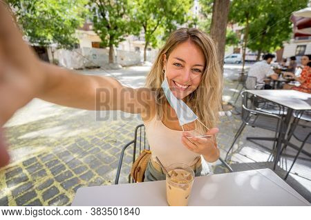 Woman Wearing Protective Face Mask On Mobile Video Calling Friends In Coffee Shop In The New Normal