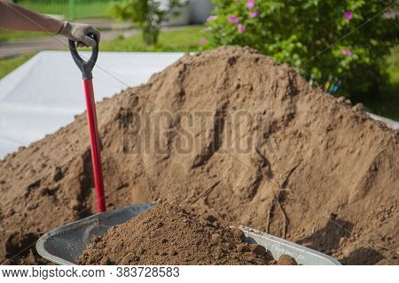 The Gardener Sprinkles A Flower Bed With A Shovel. Creation Of Landscape Design In The Garden. The M
