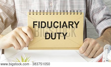 Text Fiduciary Duty Is Written On A Notebook With A Pen And A Magnifying Glass Lying On The Table. B