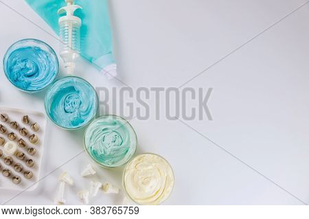 Pastry Bag With Nozzles And Blue Icing On White Background.