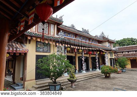 Hoi An, Vietnam, February 21, 2020: Facade Of The Chùa Phước Lâm Temple With Bonsai Trees In The Cou