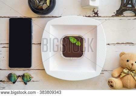 Top View Chocolate Fudge Cake With Peppermint In A White Plate On A White Wooden Table With A Mobile