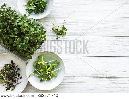 Assortment Of Micro Greens On White Wooden  Background, Copy Space, Top View. Red Radish, Green Peas