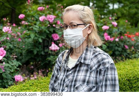 Middle Aged Mixed Race Blonde Woman With Eyeglasses Wearing White Surgical Mask. Protection Against 