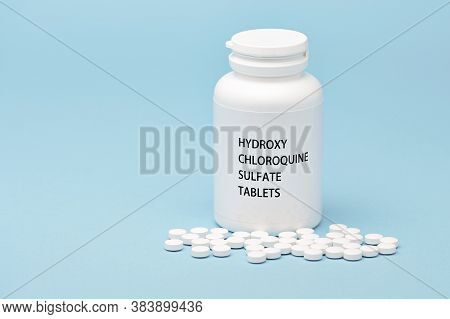 Hydroxychloroquine In White Bottle Packaging With Scattered Pills. Isolated On Blue Background. Trea