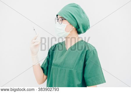 Portrait Of Young Surgery Nurse/doctor Looking At A Syringe Needle Preparation For Injection. Health