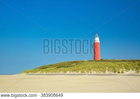 Lighthouse At Northern Beach Of Island Texel In Netherlands On Summer Day With Blue Sky