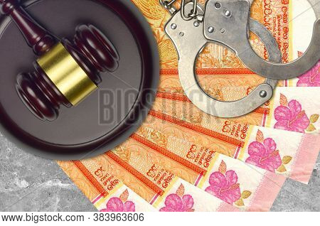 100 Sri Lankan Rupees Bills And Judge Hammer With Police Handcuffs On Court Desk. Concept Of Judicia
