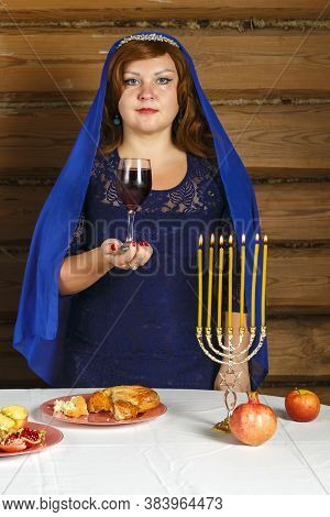 On The Eve Of Rosh Ashan, A Jewish Woman Stands Next To Burning Candles With A Glass Of Kiddush Wine