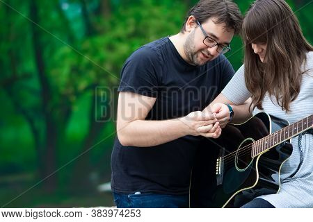 Older Brother Teaching His Younger Sister To Play Guitar In The Nature. Beautiful Moments Spent Toge