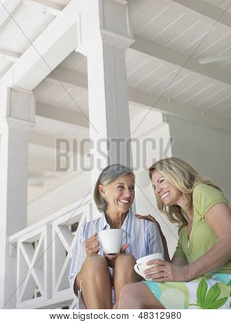 Két boldog középkorú nők ült a veranda csésze kávé