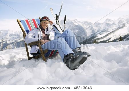 Ritratto di donna sorridente seduto sulla sdraio in montagne innevate