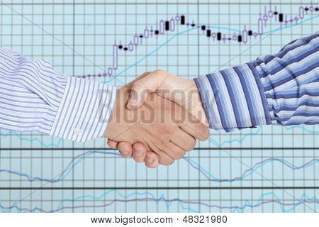 Closeup obchodní handshake mezi dvěma kolegy na pozadí burzy