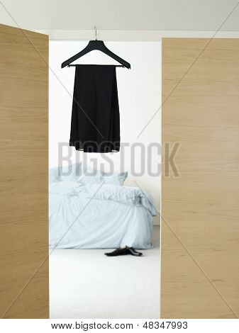 Zwarte jurk op de hanger in de deuropening van slaapkamer thuis