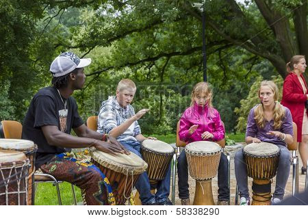 Black Musician From Africa Demostrates How To Play The Drums To Local Children