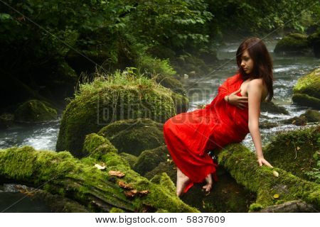 Ragazza in rosso in un ruscello