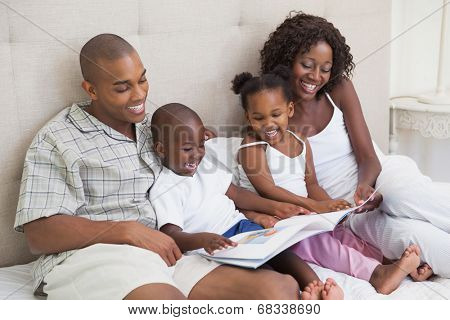 Happy family lying on bed reading book at home in the bedroom