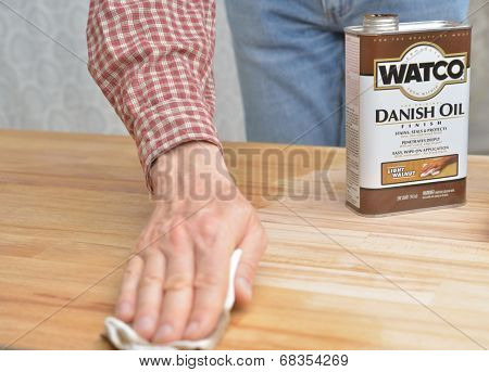 DNEPROPETROVSK, UKRAINE - MAY 30, 2014: Man applying the Watco Danish oil to the wood. Watco is one of brands owned by Rust-oleum corporation which provides solutions in surface protection since 1921