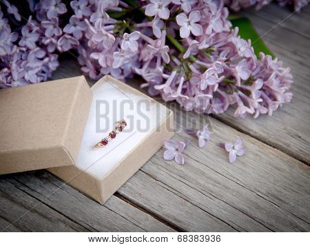 Ring In Gift Box And Lilac On Wood