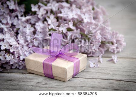 Gift Box With Purple Bow And Lilac On Wood