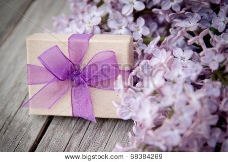 Gift Box With Purple Bow And Lilac On Wood