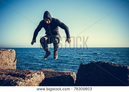man performs freerunning jump on stones