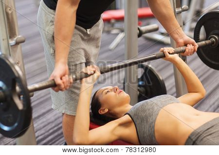 sport, fitness, teamwork, weightlifting and people concept - young woman and personal trainer with barbell flexing muscles in gym