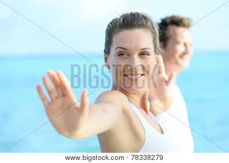 Couple doing yoga and relaxation exercises by the sea