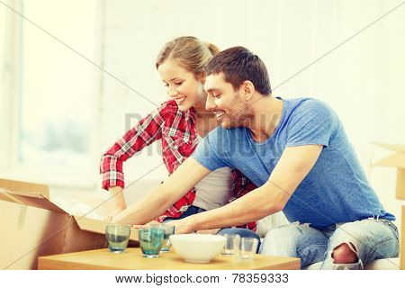 repair, building and home concept - smiling couple unpacking kitchenwear