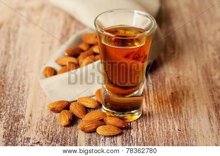 Dessert liqueur Amaretto with almond nuts, on wooden table