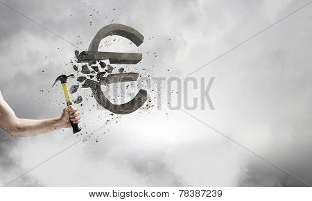 Close up of hammer in human hand breaking stone euro symbol