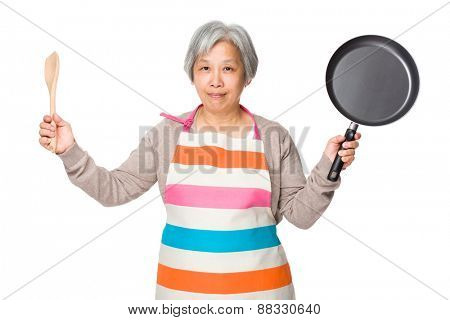 Old woman hold up with wooden ladle and fried pan