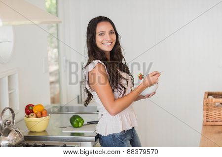 Pretty brunette eating a salad in the kitchen