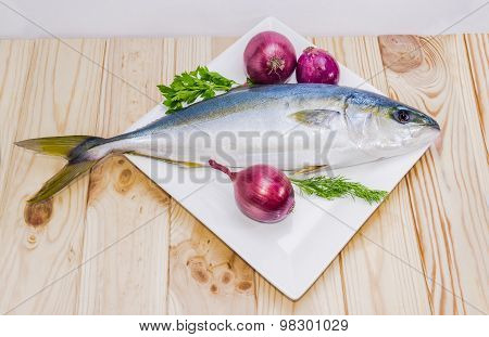 Whole Round Fish Yellowtail And Red Onion On A Wooden Surface