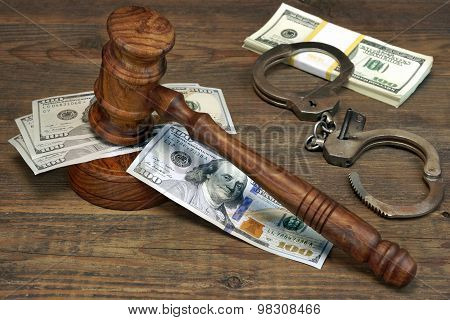 Dollar Cash, Handcuffs And Judge Gavel On Wood Table
