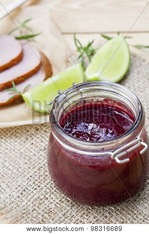 Home made organic cherry jam confiture, smoked meat and lime on a wooden table