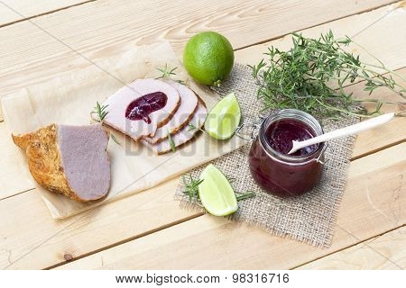 Home made organic cherry jam confiture, smoked meat and lime on a wooden table