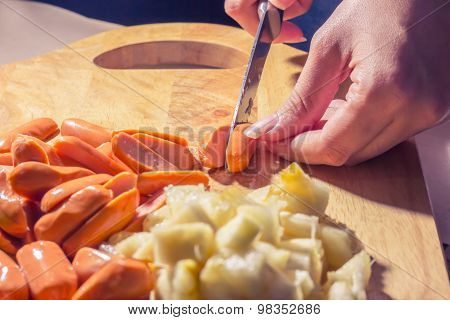 Preparing sausage and vegetables woman hands vintage tone.