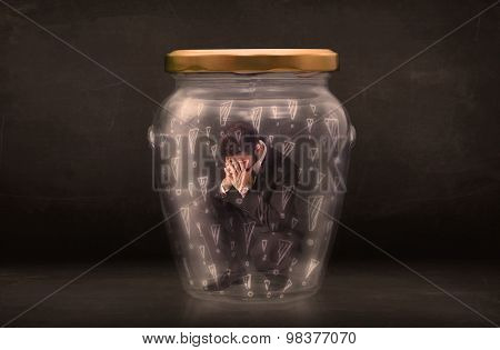 Business man trapped in jar with exclamation marks concept on bakcground