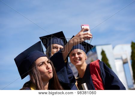 Capturing a happy moment.Students group  college graduates in graduation gowns  and making selfie photo