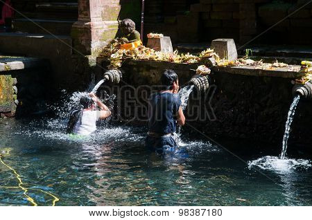 A man bathes in holy water pool in Tirta Empul temple
