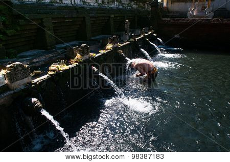 A man bathes in holy water pool in Tirta Empul temple