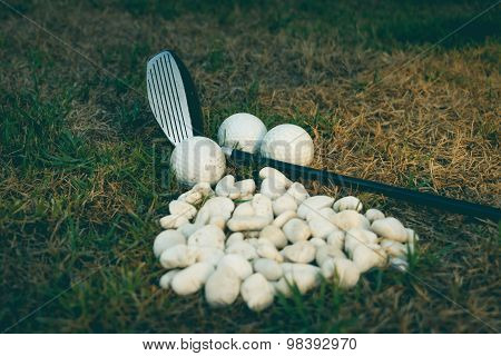 Golf Ball And Golf Club Beside Mini Stone On The Grass