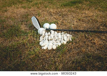 Golf Ball And Golf Club Beside Mini Stone On The Grass
