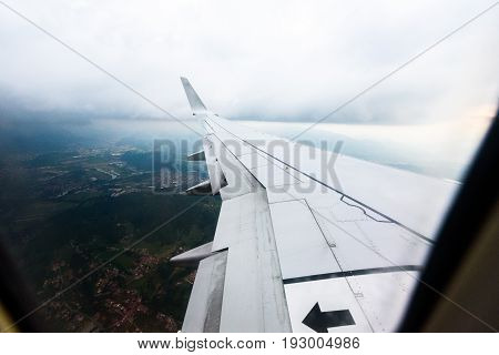 Looking trough window of an aircraft airplane or plane wing. View from plane window during landing or takeoff over the city urban area.